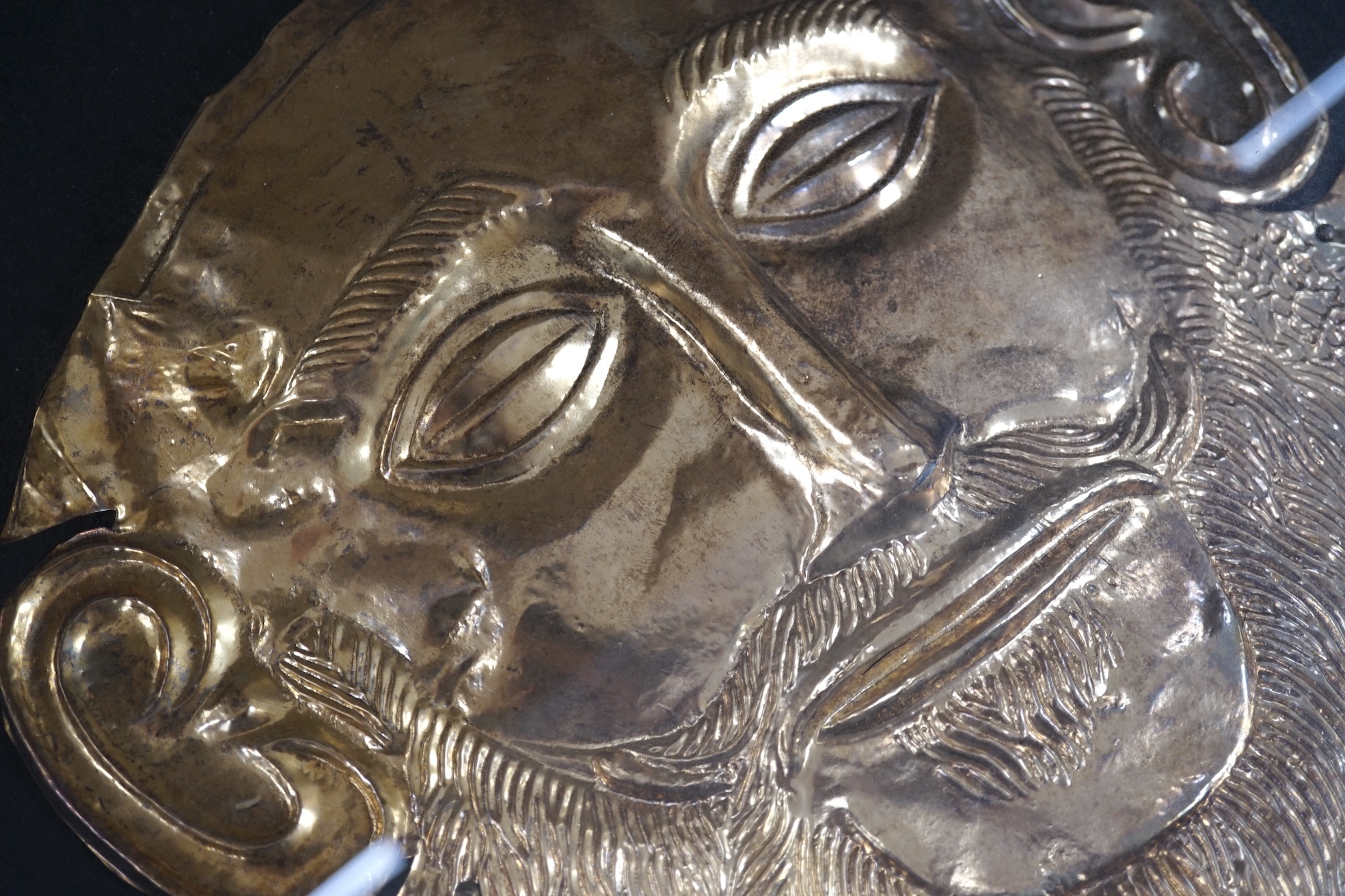 A museum type replica of an Agamemnon mask, copied from the gold mask of the king from the fifth Royal tomb on the Acropolis of Mycenae, 16th century B.C., made in Greece. Condition - good.